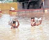 Residents of Kamatagi, Bagalkot district, wade through a flooded street on  Saturday. KPN