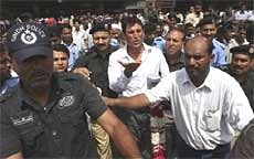 Police officers escort Younus Khan, centre, hand raised, captain of Pakistani cricket team upon his arrival in Karachi Monday. AP