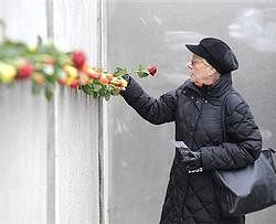 A woman places a rose into part of the former Berlin wall during a commemoration event to mark the 20th anniversary of the fall of the Berlin Wall. AP