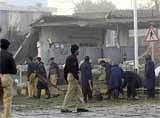 Police officers collect evidence at the spot of a suicide bombing in ISI office in Peshawar, on Friday. AP