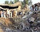 Residents gather at the site of car bombing at a police station in Badh Ber, near Peshawar on Monday. AP