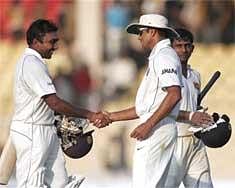 Indian cricketer Rahul Dravid (C), congratulates Sri Lankas Mahela Jayawardene (L), for scoring a double century in the first Test cricket match at Ahmedabad, Wednesday. PTI