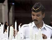 A policeman lights candles outside Trident hotel to pay tribute to the victims of 26/11 Mumbai terror attack, in Mumbai on Thursday. PTI