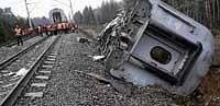 Deadly tracks: Railroad workers stand next to a damaged coach at the site of a train derailment near the town of Uglovka, some 400 km north-east of Moscow, Russia, on Saturday. AP