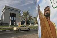 a taxi passes the Gate building, left, of Dubai International Financial Center, DIFC, and a billboard of Sheik Mohammed bin Rashid al-Maktoum, United Arab Emirates prime minister and ruler of Dubai in Dubai, United Arab Emirates.