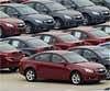 In this Oct. 30, 2009 file photo, a man walks through a parking lot occupied by Chevrolet Cruze models at a local joint manufacturer with Shanghai GM in Shengyang, in northeast China's Liaoning province. AP