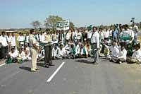 The members of the Rajya Raitha Sangh and Hasiru Sene staging a protest on the four-lane bypass road on NH 7 on the outskirts of Chikkaballapur. The members demanded service roads on either sides of the bypass road. dh photo