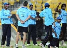 Sri Lankan cricket captain Kumar Sangakkara (L) gestures as his teammates warm-up during a practice session at Mohali. AFP