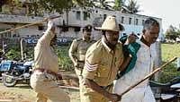 Police caning a farmer in Chamarajnagar on Friday. dh Photo