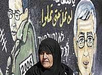 A Palestinian woman is seen in front of a mural, depicting captured Israeli soldier Gilad Schalit as a young man and an older man, in Jebaliya, northern Gaza Strip, on Tuesday. AP