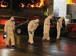 Members of Greece's counter-terrorism squad comb the street for bomb fragments outside the Ethniki Insurance building following a blast, in Athens late Sunday. AP