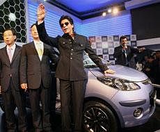 Bollywood actor and Hyundai brand ambassador Shahrukh Khan gestures as he poses with company officials during the unveiling of Hyundai i10 Electric car at 10th Auto Expo 2010 at Pragati Maidan in New Delhi