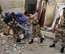 Pakistani police officer and volunteers remove a dead body at a site of the explosion in Karachi, Pakistan on Friday. AP
