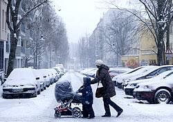 A woman and her children cross a street during a heavy snow fall in Berlin, Germany, on Saturday, AP