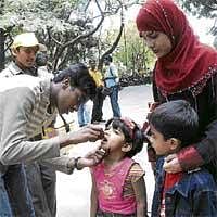 Securing Their Future: A volunteer administering  pulse polio drops to a child at Cubbon Park in Bangalore on Sunday. DH Photo