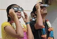 Forward Looking: The newly-wedded Spoorthi and Nagaraj viewing the eclipse after exchanging garland at Chitradurga on Friday. DH Photo