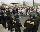 Protesters march past Phoenix police officers in riot gear during a march against Maricopa County Sheriff Joe Arpaio and his immigration efforts on Saturday in Phoenix. AP