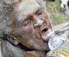 Earthquake victim Anna Zizi drinks water after being carried alive from the rubble of Haitis devastating earthquake on Tuesday, one week after the city was reduced to ruins. AP