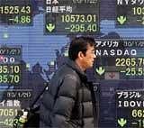 A man walks past an electronic stock board of a securities firm in Tokyo on Friday.The Nikkei 225 Stock Average dived 277.86 points, or 2.6 percent, to 10,590.55. AP