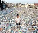 A boy stands amid plastic waste from a plastic bottle recycling plant in a slum area in Mumbai. AP