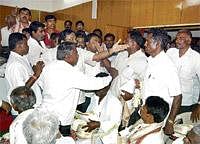 Friction:  Panchayath president M Srinivasan trying to calmfighti8ng farmers as cChaos prevailed at the seminar and distribution of subsidy to farmers, organised by the Sericulture Department at Kolar on Friday.  DH Photo