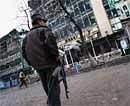 An Afghan security officer stands guard outside the Park Residence guesthouse (L) and Kabul City Center shopping center (R), the site of the gun battle and explosions, in the Shar-e Naw area in the heart of the capital Kabul on February 26, 2010. AFP