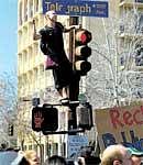 A UC Berkeley student climbs on a street light during a march against funding cuts and tuition hikes. AFP