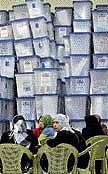 Electoral workers sit in front of stacked ballot boxes at a counting centre in Baghdad on Monday. AP