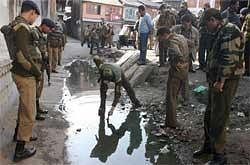 Police and CRPF personnel inspect the spot where a grenade exploded in downtown area of Srinagar on Sunday. Four CRPF personnel and a civilian were injured in the blast. PTI