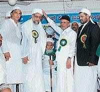 Pattikkad Jamia Nooriya President Syed Hyder Ali Shihab Tangal Panakkad placing a turban on the head of Twakha Ahmed Musliar, marking the latters elevation as the new Qazi of Dakshina Kannada at the Zeenath Baksh Central Jumma Masjid at Bunder in Mangalore on Saturday. DH photo