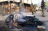 Security personnel near a burning bike during the sectarian violence at Gowliguda in Hyderabad on Sunday. PTI