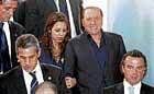 Italian Premier Silvio Berlusconi (center right) is escorted by a People of Freedom Party election observer as he leaves the polling station after casting his ballot in Milan on Sunday. AP