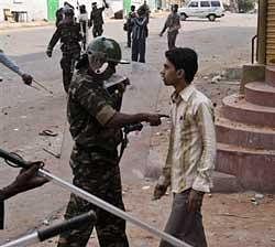 An Indian policeman reprimands a boy for throwing stones at members of another community in the old city area of Hyderabad, India, Monday, March 29, 2010. Authorities fired tear gas and warning shots and swung batons Monday to disperse crowds of angry Hindus and Muslims who attacked each other with stones and clubs in southern India, where dozens of people have been injured. (AP