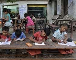 Children attend a school set up on a footpath in Ahmedabad on Friday, April 2, 2010. The footpath school is run by 62-year-old Kamal Parmar who started giving evening classes to children, mostly from slum areas, more than ten years ago. AP