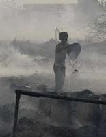 A man pours water to help douse a fire at a slum area in Ghazipur, on the outskirts of New Delhi, India, Thursday, April 8, 2010. The fire was reportedly started after a power transmission line fell. Some 600 shanties were gutted but no casualties were reported, according to the fire department. (AP)