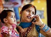 india calling:  A woman holds a child as she talks on a mobile phone in Allahabad on Friday.  AP
