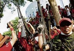 no stopping: Anti-government protesters hold up weapons they seized from soldiers at Thaicom Teleport and DTH Centre on the outskirts of Bangkok. reuters