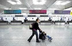 grounded: A woman pushes a buggy past empty check-in desks at Stansted Airport in Essex, eastern England, on Saturday, as volcanic ash from Iceland halted thousands of flights. AFP