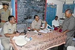 Superintendent of Police Dr K Tyagarajan listening to a complainant, after inaugurating Complainants / Victims Day at the town police station in Kolar on Sunday. Town Circle Inspector Nandakumar is also seen. DH Photo