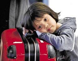 Long wait: A girl rests on her suitcase in a terminal at the airport in Frankfurt, central Germany, on Sunday. AP