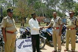 Superintendent of Police Dr K Thyagarajan handing over the key of a recovered vehilce to its owner in Kolar on Monday. DH photo