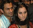 Pakistani cricketer Shoaib Malik, left, escorts his wife Indian tennis star Sania Mirza as they arrive at a local hotel in Lahore