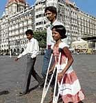 crippled but not defeated: Devika Rotwan, who was shot in her leg during the Mumbai  attacks, walks by the landmark Taj Hotel in Mumbai on  Monday. AP