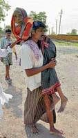 A man carrying his grandmother to a polling booth at Harobelavadi in Dharwad on Wednesday. dh photo