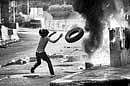 An anti-government protester tosses more tires on a fire in front of a stand off with Thai military, on Sunday, in Bangkok, Thailand. AP