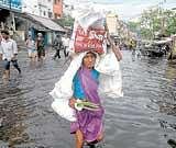 A woman carries a load as she wades through a flooded street after heavy rains in Visakhapatnam on Thursday.  Reuters