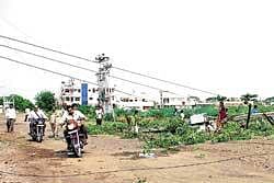 gone with the wind:  A rider trying to pass under the  electric wires of an uprooted electricity pole in Bijapur on Thursday. dh Photo