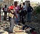 Somalia pro-government Ahlusunna fighters stand over one of two dead bodies of alleged Shebab militants who were killed by the pro-government Ahlusunna fighters after apprehending them near a frontline in southern Mogadishus Bakara neighborhood on May 20. AFP Photo