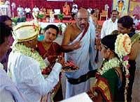 Priest distributing mangalsutra to the couples who were getting wedded at Hornadu Sri Annapurneshwari temple on Monday in a mass marriage ceremony. DH Photo