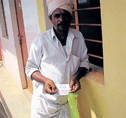 A farmer from Mavalli, who had applied for a certificate, shows a receipt with out any details on Thursday. DH Photo